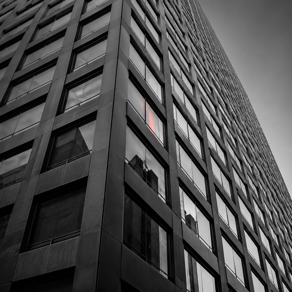 High-rise facade in black and white with a red reflection